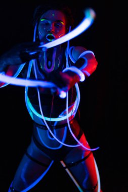 Neon UF Işık 'ta Parlayan Tüplü Bir Kızın Portresi. Dreadlocks ve Flüoresan Yaratıcı Psikedelik Makyajlı Model Kız, UV 'de Kadın Disko Dansçısı Modeli, Renkli Soyut Makyaj
