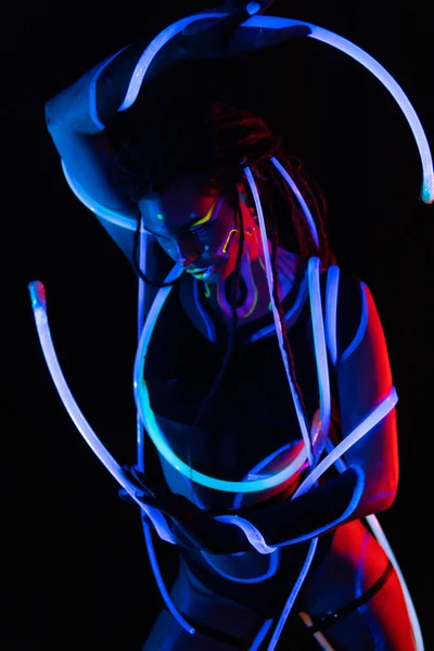 Portret van een meisje met gloeiende buizen in Neon UF Light. Model Girl with Dreadlocks and Fluorescent Creative Psychedelic MakeUp, Art Design of Female Disco Dancer Model in UV, Kleurrijk Abstract Make-up — Stockfoto