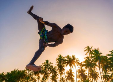 Beyaz Kum Sahili Akrobasi Eğitiminde Genç Çekici Kaslı ve Güçlü Siyah Afrikalı Adam ve Gün batımında Atlayan Jimnastik Sahili Gösterisi