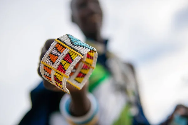 Masai Tribal Female Holds a Colorful Souvenir Bracelet for sale for tourist. Traditional Maasai Village Engare Sero in Tanzania, Arusha, Natron Lake — Stock Photo, Image
