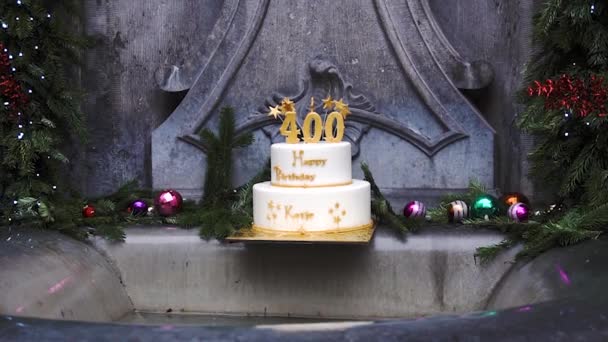 Los 400 años de cumpleaños de la famosa estatua de The Manneken Pis, Bruselas, Bélgica. Peeing Boy en suite y pastel de cumpleaños con número 400 — Vídeos de Stock