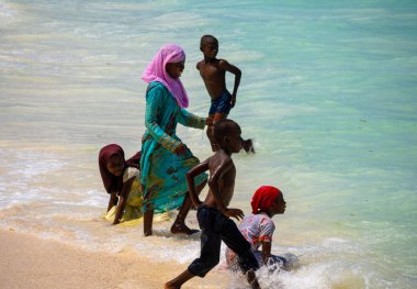 Nungwi, Zanzibar - Aralık 2019: Turkuaz Sudaki Erkekler ve Kızlar. Kuzey Zanzibar 'daki Nungwi köyünde Sunny Day' de Okyanus Dalgaları 'nda oynayan Afrikalı çocuklar.