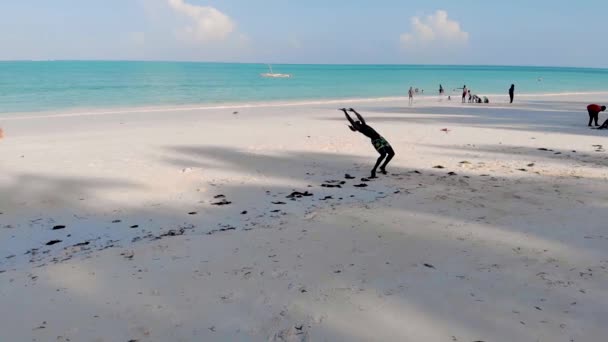 若い魅力的な筋肉と強いアスレチックブラックアフリカの男クリスマスハットトレーニングアクロバットと白い砂浜のパフォーマンスで体操をジャンプ — ストック動画