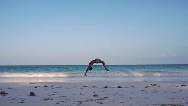 Jonge aantrekkelijke gespierde en sterke atletische zwarte Afrikaanse man training acrobatiek en springen gymnastiek bij de White Sand Beach Performance — Stockvideo