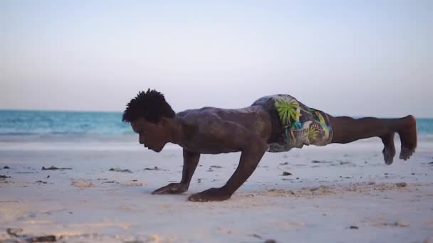 若い魅力的な筋肉と強い運動黒アフリカの男性トレーニングアクロバットと白い砂浜のパフォーマンスで体操をジャンプ — ストック動画