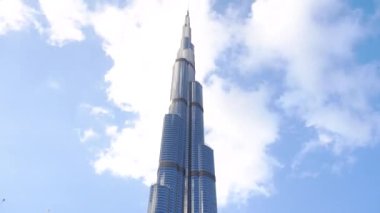 Burj Halife 'nin üzerinde, mavi gökyüzünün arasında, dünyanın en yüksek binasında koşan Bulutların Zamanı. Dubai, BAE