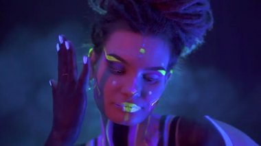 Neon UF Light 'ta Dreadlock' lu bir kızın portresi. Flüoresan Yaratıcı Psikedelik Makyajlı Model Kız, UV 'deki Kadın Disko Dansçısı Modeli, Renkli Soyut Makyaj. Dans eden bayan.