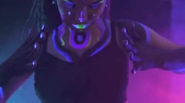 Neon UF Light 'ta Dreadlock' lu bir kızın portresi. Flüoresan Yaratıcı Psikedelik Makyajlı Model Kız, UV 'deki Kadın Disko Dansçısı Modeli, Renkli Soyut Makyaj. Dans eden bayan.