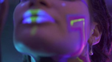 Neon UF Light 'ta Dreadlock' lu bir kızın portresi. Flüoresan Yaratıcı Psikedelik Makyajlı Model Kız, UV 'deki Kadın Disko Dansçısı Modeli, Renkli Soyut Makyaj. Dans eden bayan.