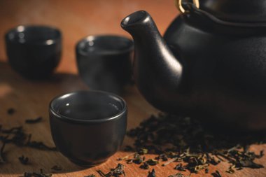 Bardak çay sıcak duman ile seramik çaydanlık yerleştirilir ve kuru çay ahşap arka plan üzerinde dağınık bırakır.