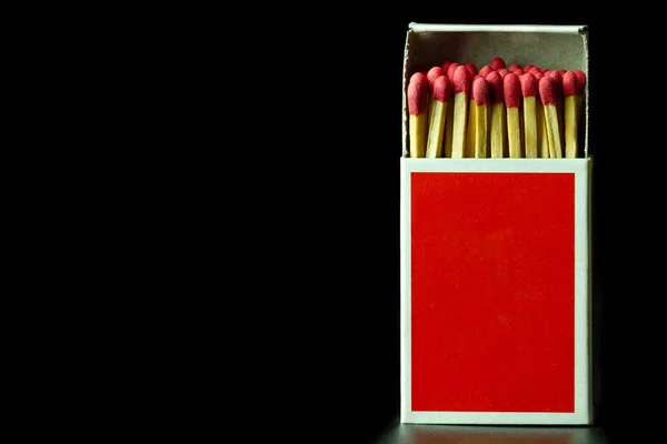 Matches stick in red paper box on black background.