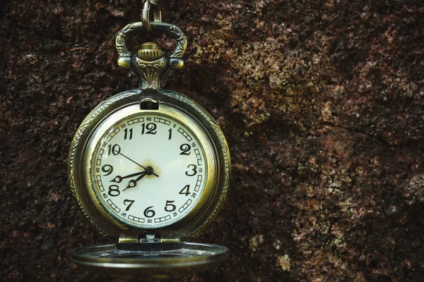 Старовинний старий кишеньковий годинник, повішений на фоні каменю . — стокове фото