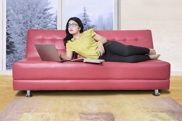 Töprengő nő és egy piros kanapé — Stock Fotó