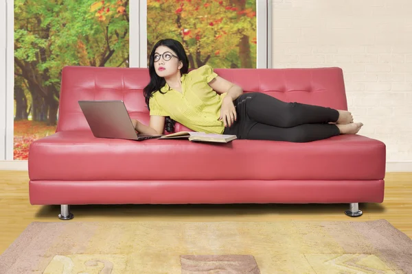 Csinos női töprengő, a piros kanapén — Stock Fotó