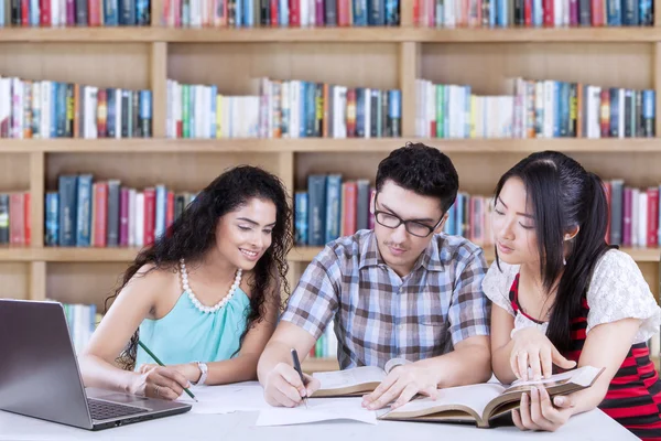 Tres estudiantes estudiando en la biblioteca — Foto de Stock