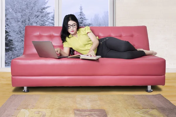 Mujer está estudiando en sofá rojo — Foto de Stock