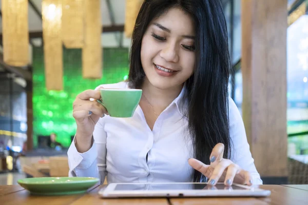 Mujer jugando tableta PC mientras bebe café — Foto de Stock