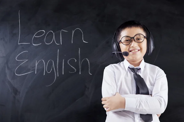 Ребенок с гарнитурой и текстом изучает английский язык — стоковое фото
