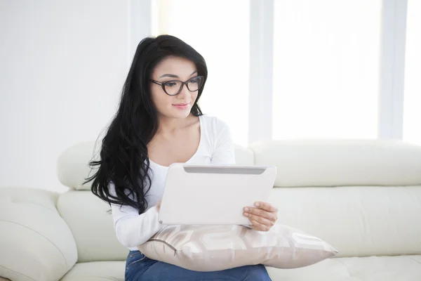 Mujer bonita utiliza tableta en el sofá —  Fotos de Stock