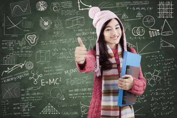 Студент в зимней одежде показывает большой палец вверх в классе — стоковое фото