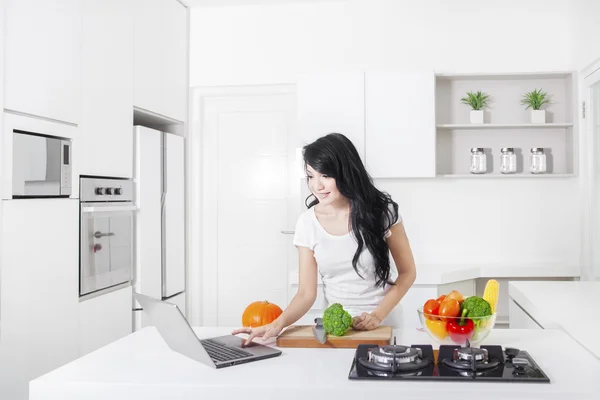 Młoda kobieta korzystająca z laptopa w kuchni — Zdjęcie stockowe