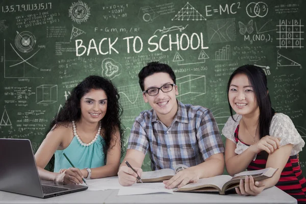 Tres estudiantes con asignación en la clase — Foto de Stock