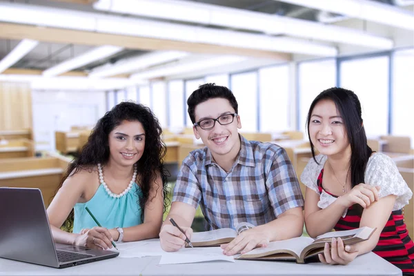 Трое студентов, пишущих в классе — стоковое фото