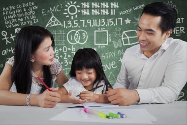 Ebeveynleri ev ödevi yapan küçük kız