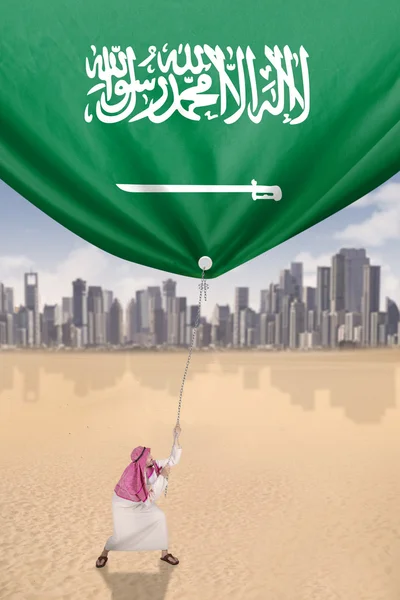 Hombre árabe tira de la bandera de Arabia Saudita — Foto de Stock