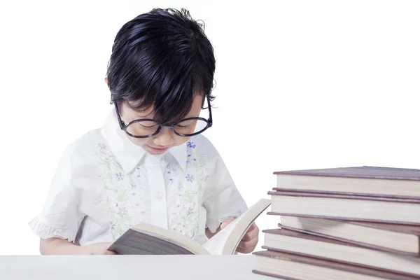 Küçük kız masada kitap okur — Stok fotoğraf