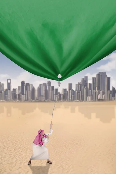 Ближневосточный человек тянет зеленый флаг — стоковое фото
