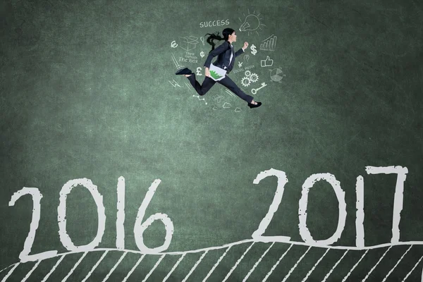 Asian worker jumps on blackboard with 2017 — Stock Photo, Image