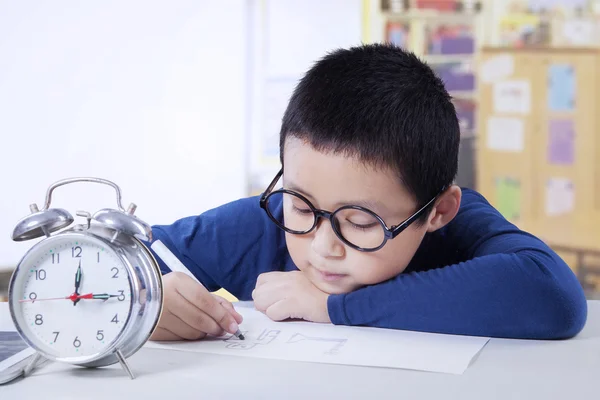 Menino aprende em sala de aula com despertador — Fotografia de Stock