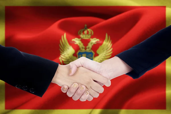 Cooperation handshake with flag of Montenegro — Stock Photo, Image