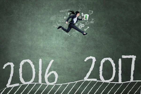 Female worker runs on blackboard toward 2017 — Stock Photo, Image