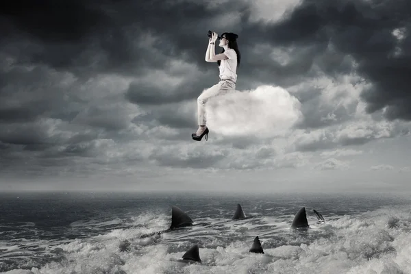 Woman with binoculars sits on the cloud — Stock Photo, Image