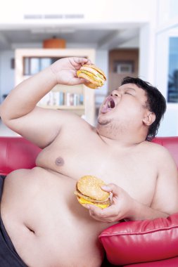 Şişman adam yeme hamburger kanepe