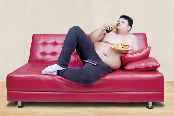 Fat man leaning on the couch — Stock fotografie