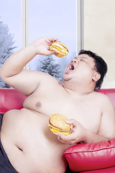 Overweight man holding two hamburgers — ストック写真