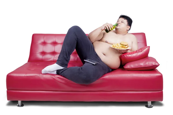 Overweight man reclining on couch — Stockfoto
