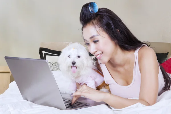 Woman and puppy typing on laptop — Stock Photo, Image