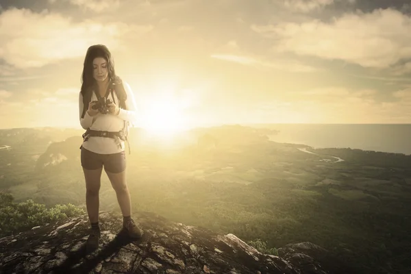 Mulher usando uma câmera em um pico de montanha — Fotografia de Stock