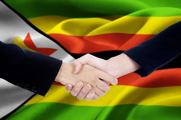Zimbabwe flag with two entrepreneurs handshake — Stock Photo, Image