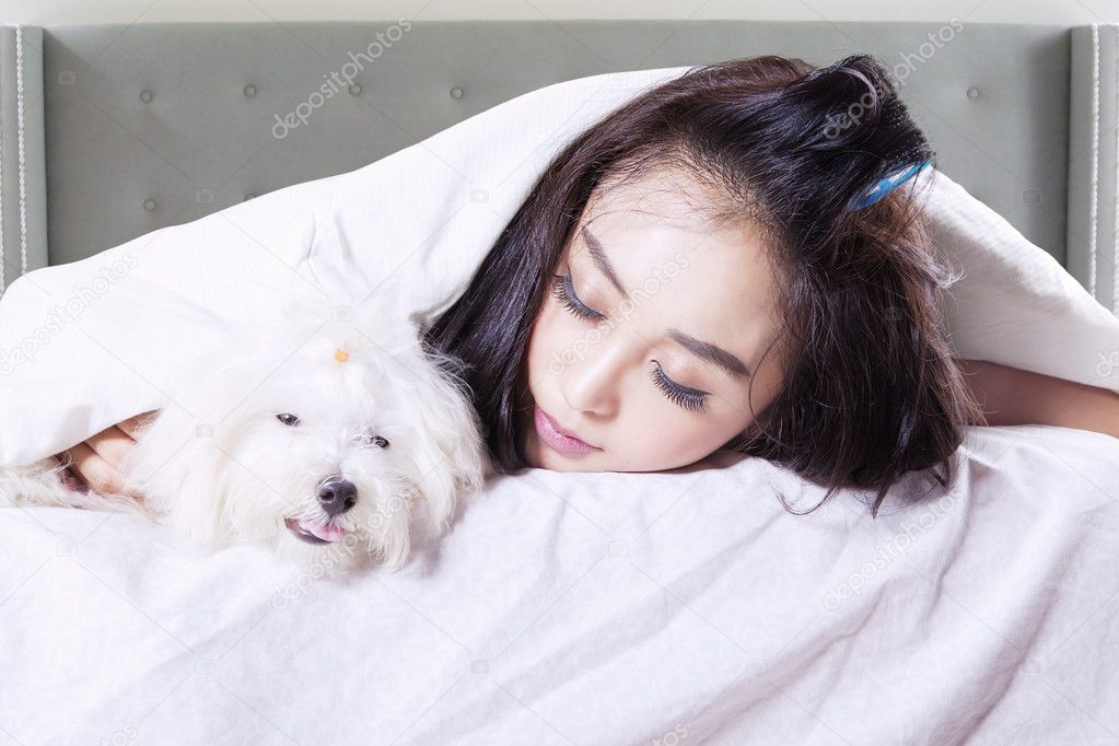 Woman and her dog sleeping under blanket