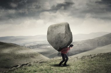 Businessman carrying rock at hill