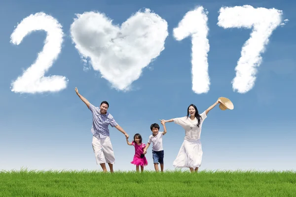 Familia alegre corriendo en el prado con 2017 — Foto de Stock