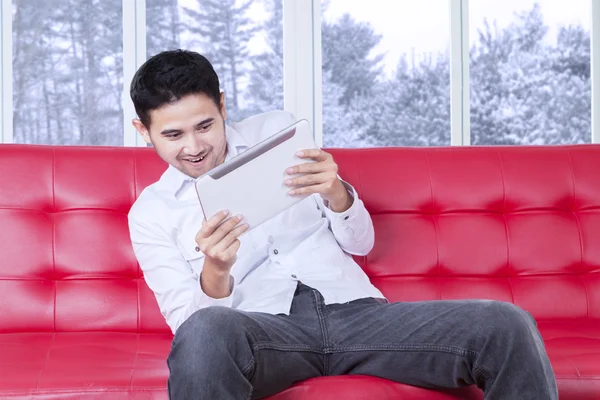 Χαρούμενη άνθρωπος χρησιμοποιώντας tablet στον καναπέ — Φωτογραφία Αρχείου