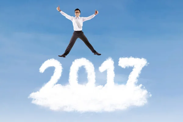 Businessman leaping above cloud shaped number 2017 — Stock Photo, Image