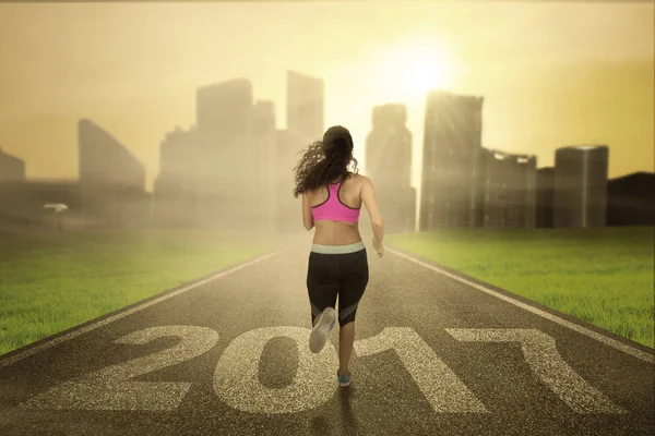 Mujer sana corre en la carretera con 2017 —  Fotos de Stock