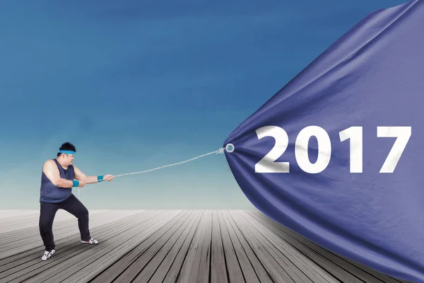 Overweight man pulling banner with 2017 — Stock Photo, Image